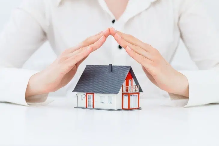 Une maison en jouet protégée par des mains