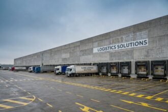 Entrepôt logistique moderne avec quais de chargement et camions, illustrant l'investissement en SCPI logistique
