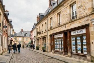 Vue d'une rue commerçante typique de l'Oise avec une agence immobilière et des bâtiments en pierre de style picard